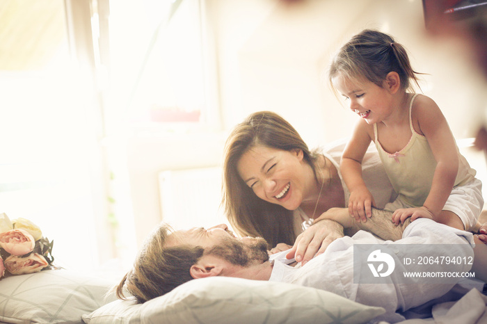 Happy family playing in bed. Space for copy.