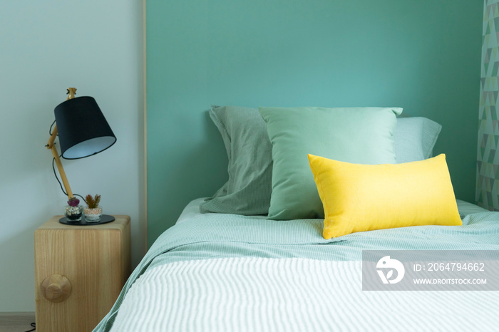 现代青少年卧室，配有绿色枕头和现代侧台灯。