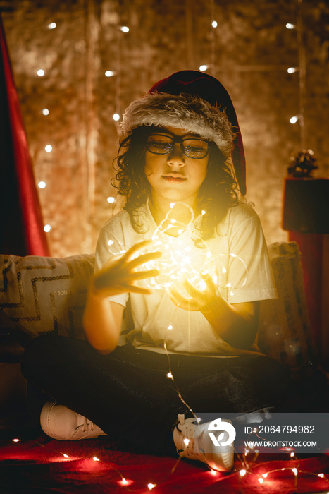Retrato de un joven adolescente con vestimenta navideña con luces cálidas en sus manos