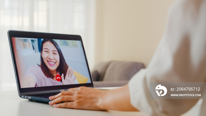 年轻的亚洲商务女性在家工作时使用笔记本电脑视频通话与朋友交谈