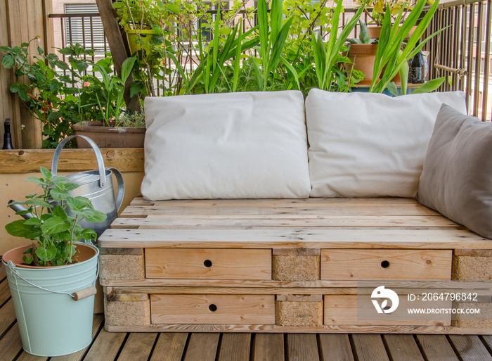 Wooden pallet couch on balcony with plants in background