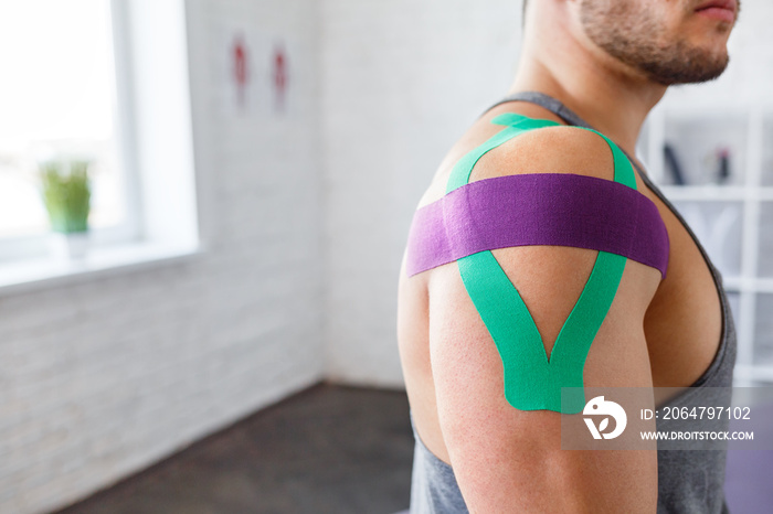 Kinesiology taping. Kinesiology tape on patient shoulder. Injured shoulder treatment of young male a