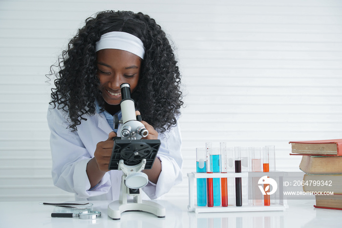 Little African girl scientist smile with a microscope and various colorful flasks and test tube at l