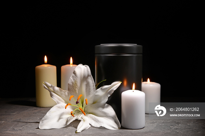 殡仪馆的骨灰盒，在黑暗的背景下燃烧着蜡烛和桌子上的鲜花