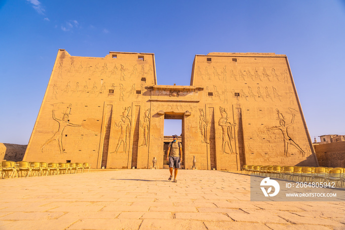 A young tourist entering the Temple of Edfu in the city of Edfu, Egypt. On the bank of the Nile rive