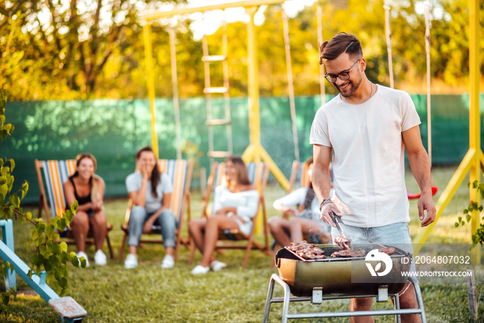 Barbecue with friends. Portrait of a man grilling meat outdoors.