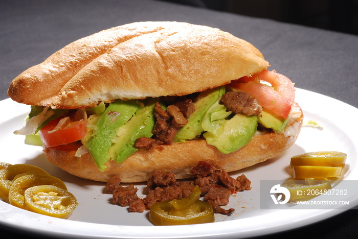 Torta de carne asada con aguacate, tomate y jalapeños