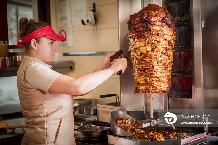 Chef preparing roasted sliced gyros meat in fast food restaurant