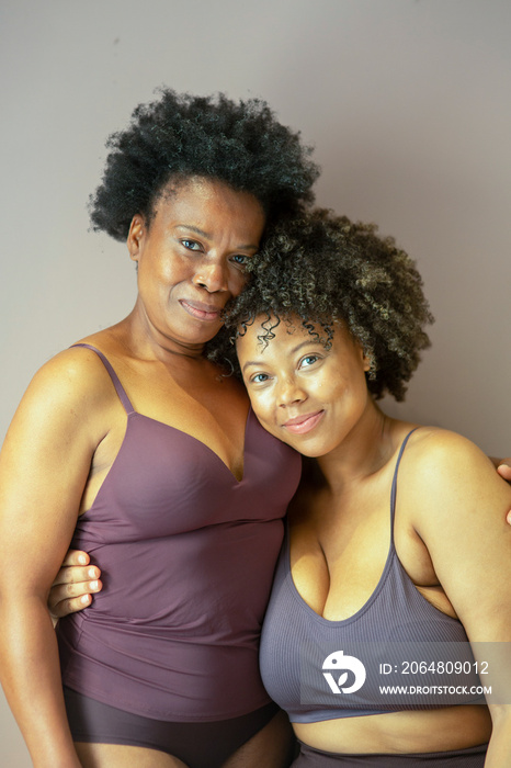Studio portrait of smiling mother and daughter wearing lingerie