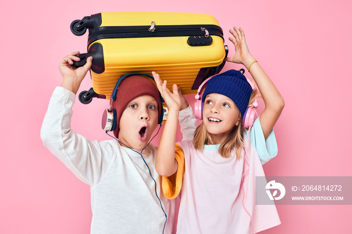 有趣的小男孩和女孩黄色行李箱带耳机工作室摆姿势