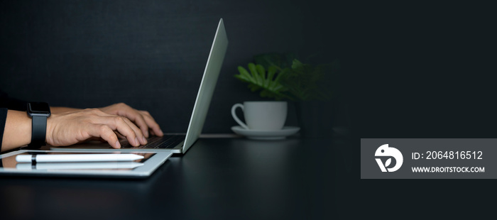 Closeup image of businessman working and typing on laptop keyboard in office.