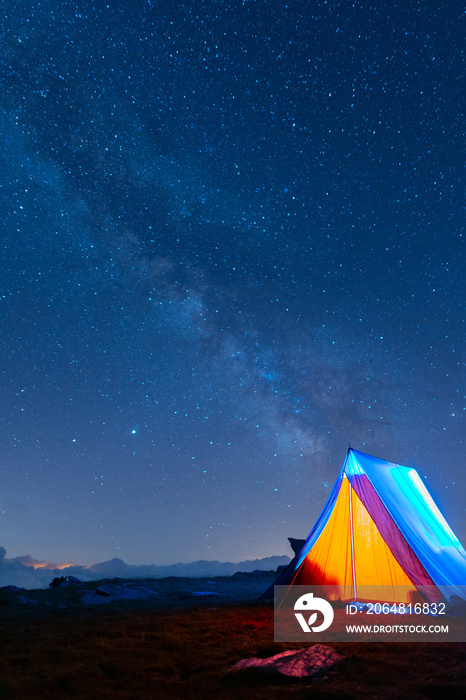 夜晚在银河下发光的帐篷。在星空下的山区露营。5