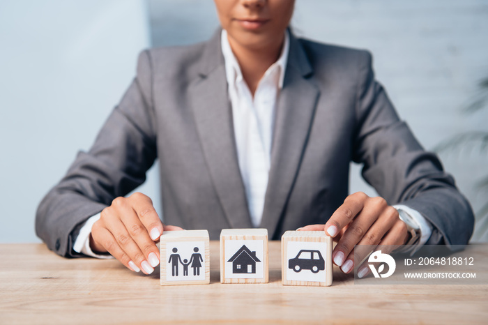 cropped view of woman touching wooden cubes with family, car and house