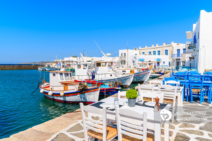 Taverna tables and typical Greek fishing boats in Naoussa port, Paros island, Cyclades, Greece