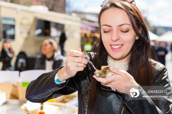 Happy smiling woman holding a single fresh opened oyster