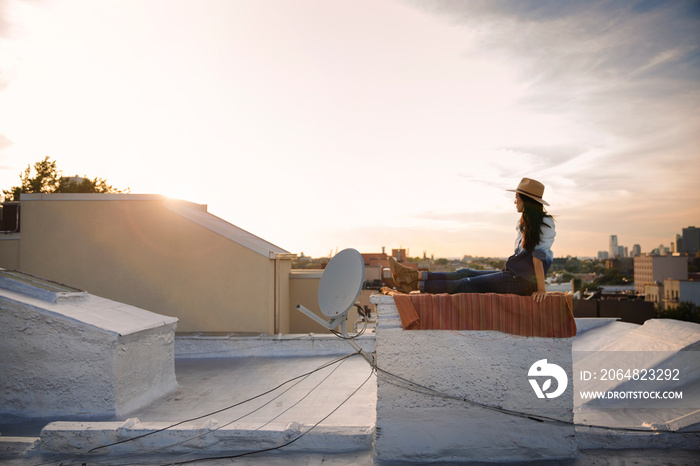 Woman sitting on blanket on rooftop