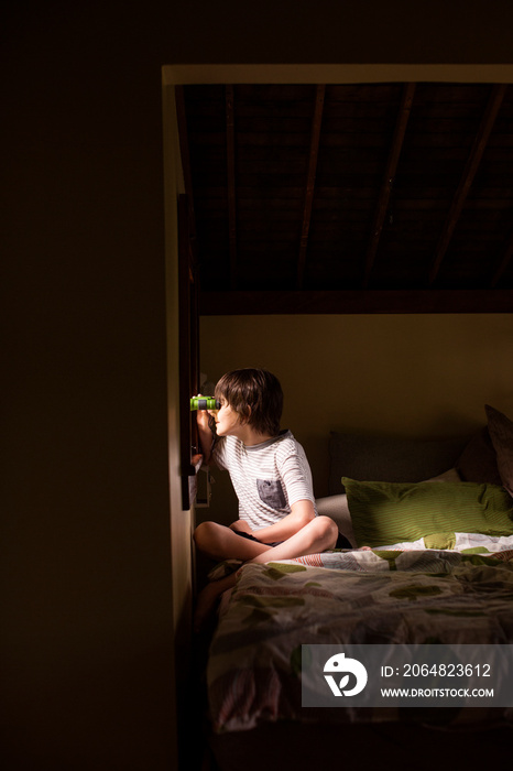 Boy looking through window with binoculars