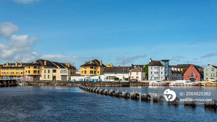 River Shannon with plastic buoys on the calm water of the river, cityscape with quaint houses in the