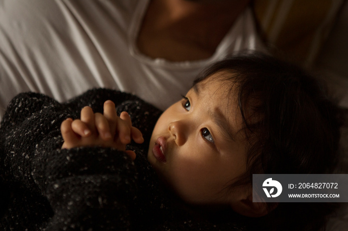 Midsection of father with cute daughter sleeping on bed at home