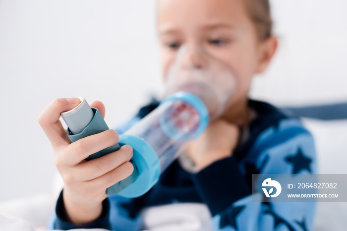 selective focus of asthmatic kid using inhaler with spacer at home