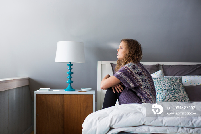 Young woman sitting on bed