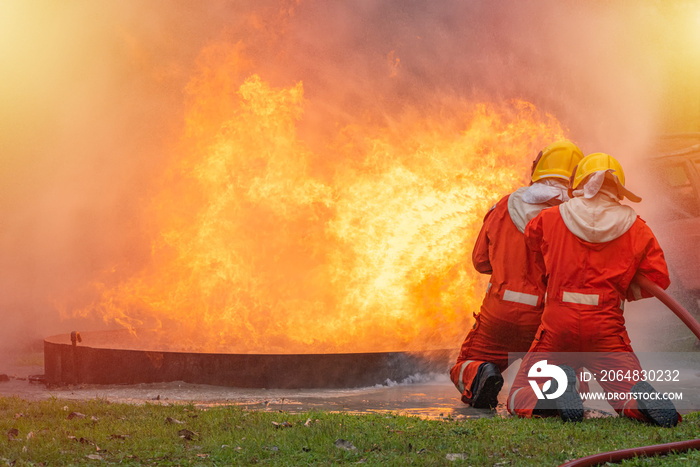 Two brave firefighter using extinguisher and water from hose for fire fighting, Firefighter spraying