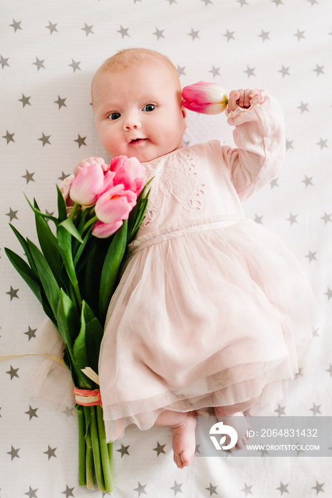 新生女婴手拿一束粉色郁金香的特写。新生活，爱和节日