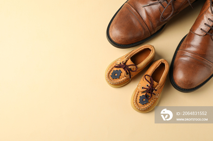 Brown leather shoes and childrens shoes on color background, space for text and top view