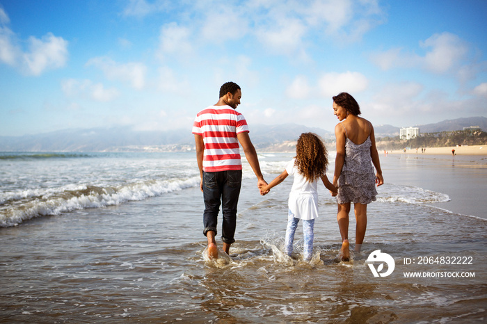 Parents with daughter (4-5) walking on beach