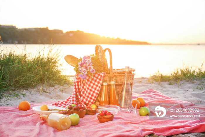 Wicker basket with tasty food and drink for romantic picnic near river