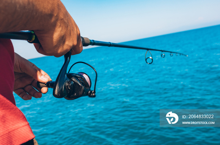 Man holding Fishing rod tackles close up. Hand with spinning reel. Fisherman standing and throw a fi