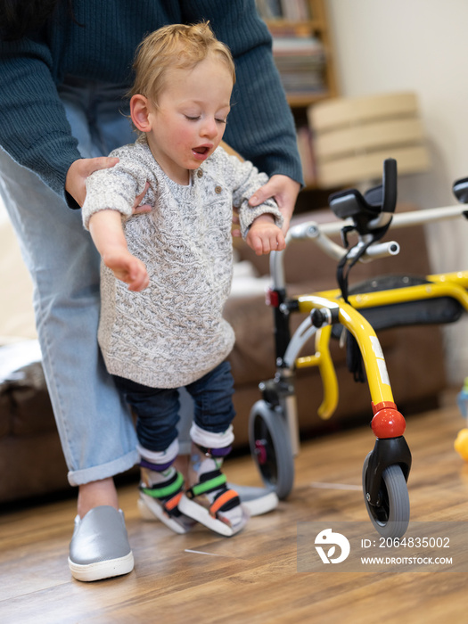 Mother assisting son with cerebral palsy in walking�