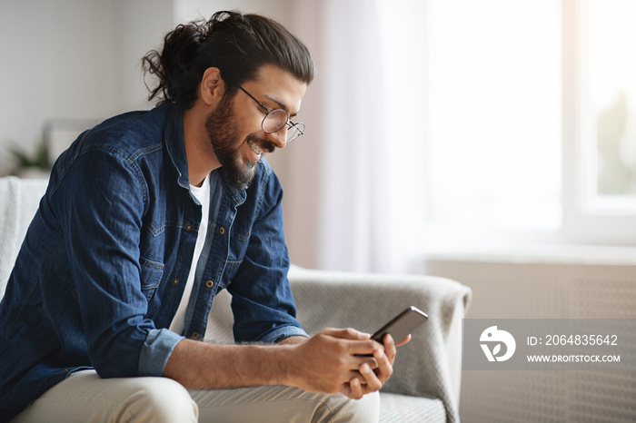 New Mobile App. Stylish Western Guy Using Smatphone At Home, Browsing Internet