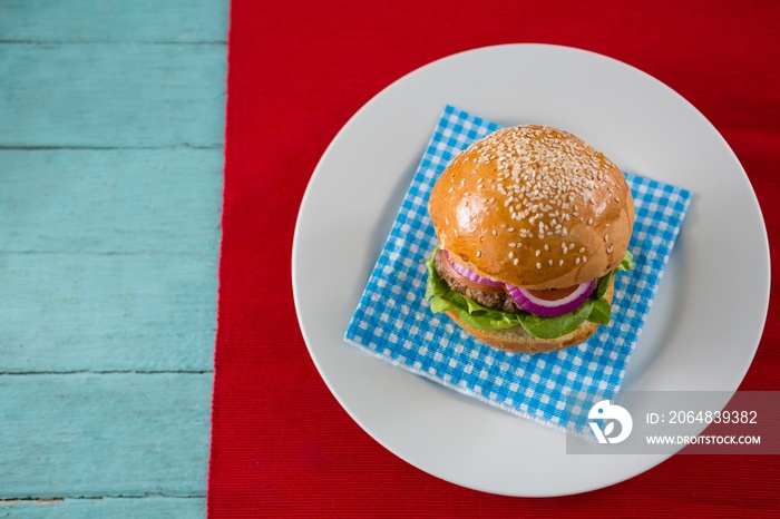 Overhead view of hamburger served on napkin in plate