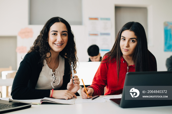 Portrait of smiling teenage students learning together in university