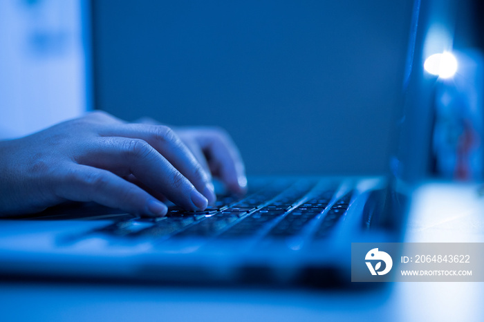 Hand of a man using laptop computer for hacking or steal data at night in office. Hacking concept