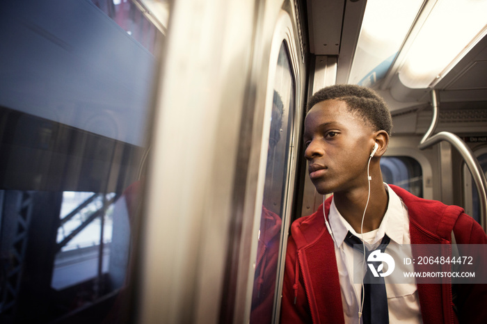 Teenage boy (14-15) listening to music in train