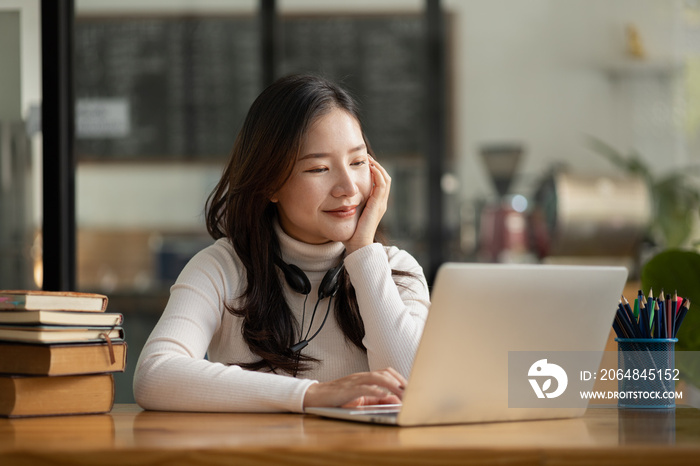 漂亮的亚洲女人用笔记本电脑在线学习，她在网上学习。在线的概念