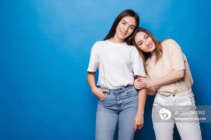 Two happy girlfriends isolated on blue background