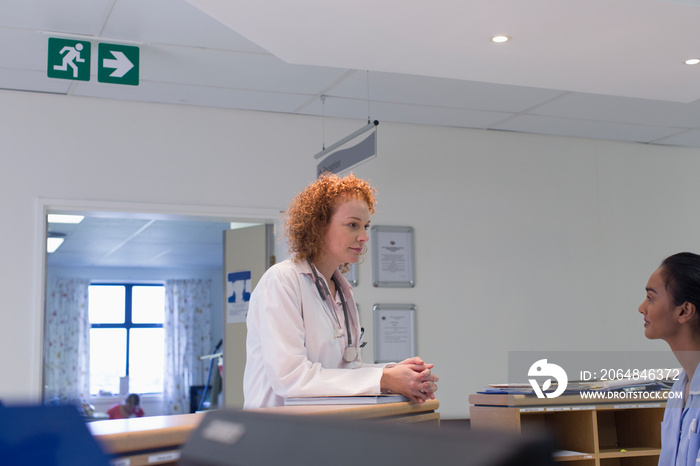 Doctor talking with nurse at hospital nurses station