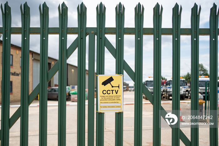 在金属安全的工业围栏上看到的闭路电视安全标志的浅焦点。围栏之外是
