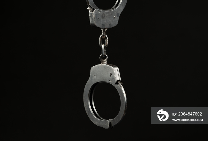 Locked police handcuffs on a black background with text / writing space