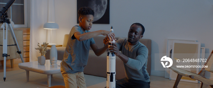 African American father and son playing together, building moon landing mission rocket together. Sta