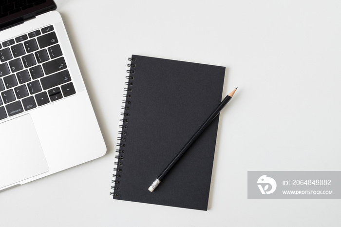 Top view desk with laptop closed black cover notebook and pencil on white desk background