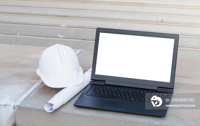 用笔记本电脑放在蓝图上的白色安全帽在施工时有白色屏幕隔离