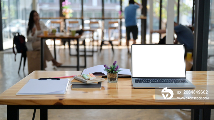 Cropped shot of laptop, notes and office supplies on a wooden desk in a comfortable shared workspace