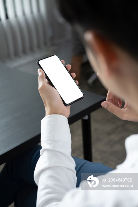 Close up over shoulder view of businessman holding mock up mobile phone with empty screen.