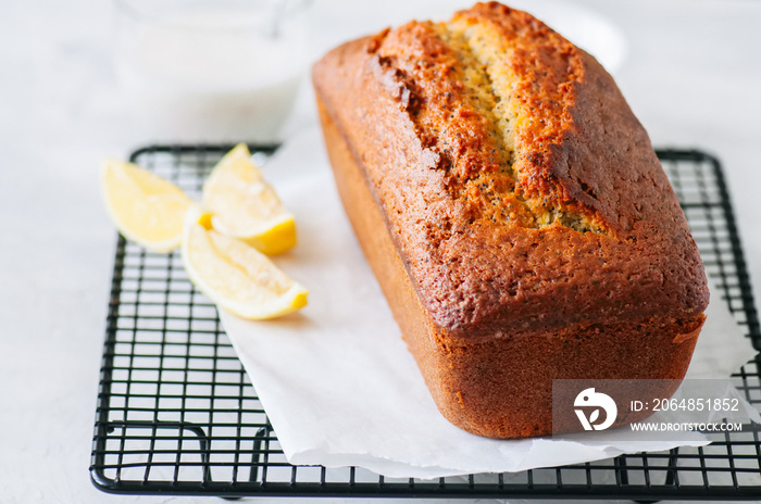 Homemade lemon poppy seed pound cake on a wire rack. White stone background.