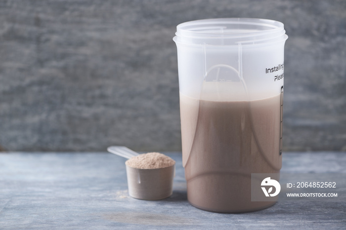 Whey protein shaker and scoop. Sport nutrition. Rustic wooden background. Copy space.