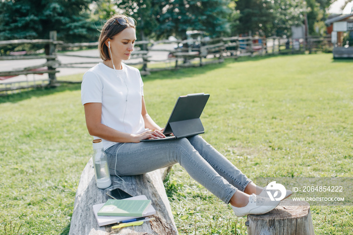 户外工作。在公园里用笔记本电脑工作的女人。隔离期间远程工作